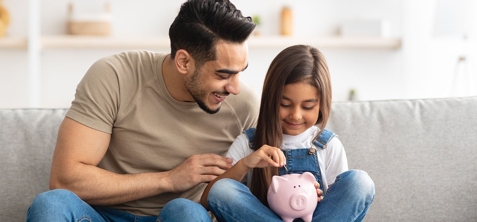 Little girl and dad saving money in piggy bank